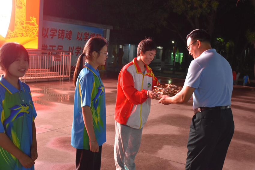 （图为学校党总支书记、校长莫荣军给学生发放月饼）.png
